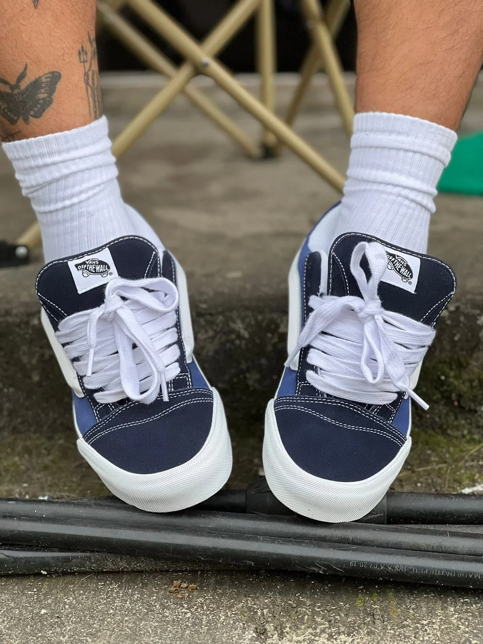 Navy Vans sneakers with white laces and white socks, worn outdoors.